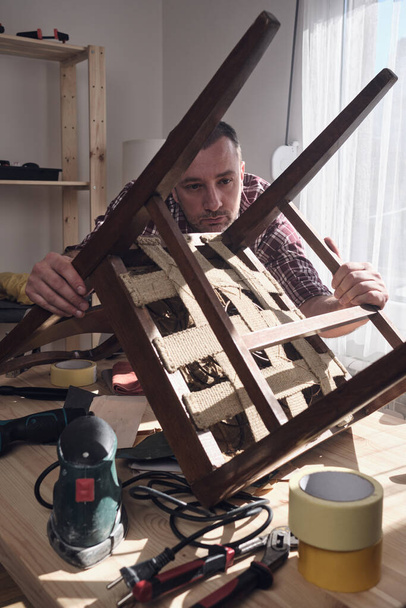 Hombre trabajando en un pequeño taller de casa para la reparación y restauración de muebles. - Foto, Imagen