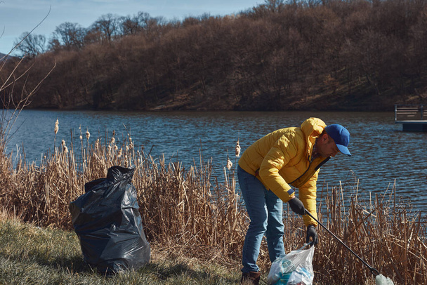 Волонтёр и эколог очищают грязное озеро от мусора. - Фото, изображение