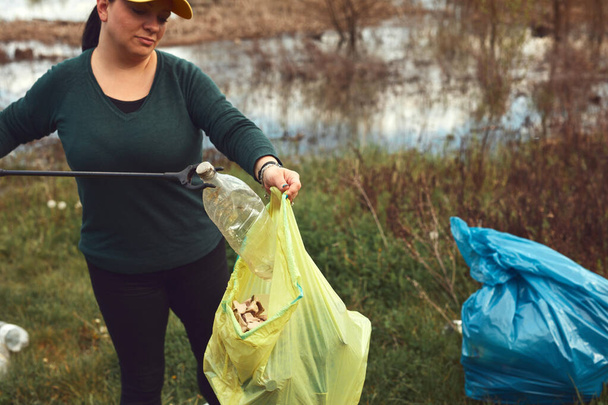 Un bénévole et militant écologiste nettoie les rives sales d'un lac rempli de déchets. - Photo, image