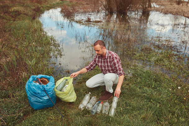 Voluntariado y activista ambiental limpiando la orilla del lago sucio lleno de basura. - Foto, imagen