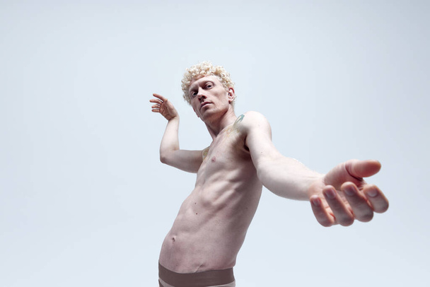 Homem loiro com tatuagens em seu corpo posando em estátua posar sem camisa isolado sobre fundo de estúdio branco. Como escultura antiga. Estética corporal masculina, beleza masculina, inspiração, conceito de arte - Foto, Imagem