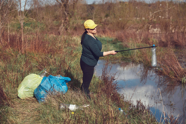 Önkéntes és környezetvédelmi aktivista takarítás piszkos tó partján tele szeméttel. - Fotó, kép
