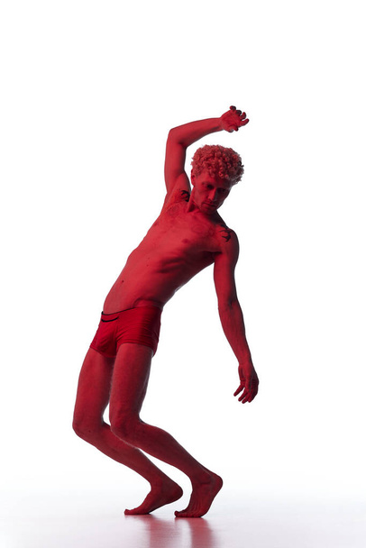 Modelo con cuerpo muscular en relieve posando en filtro de neón rojo sin camisa como estatua aislada sobre fondo blanco. Escultura masculina antigua. Concepto de estética corporal masculina, belleza masculina, arte - Foto, imagen