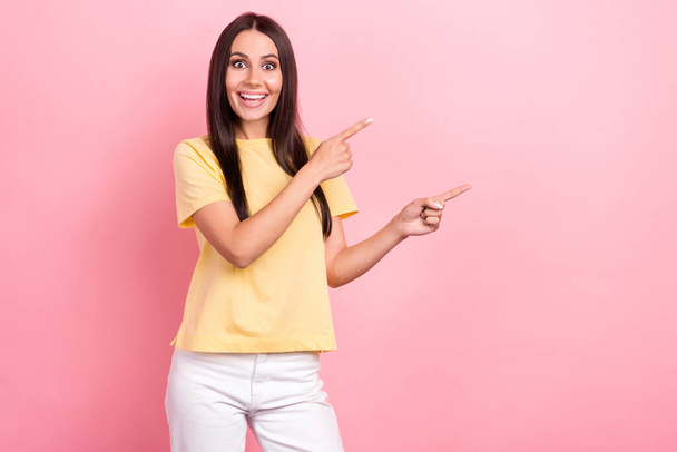 Photo attractive woman propose low price shopping direct fingers empty space banner wear yellow shirt isolated pink color background. - Photo, Image