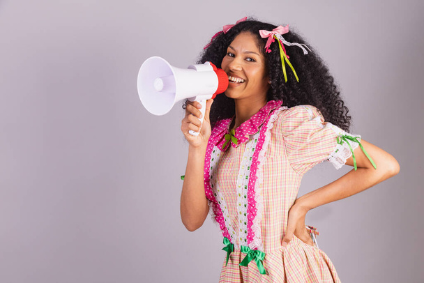 brazilian woman wearing typical clothes of festa junina, arraial, festa de so joo. shouting promotion advertising with megaphone.  - Foto, immagini