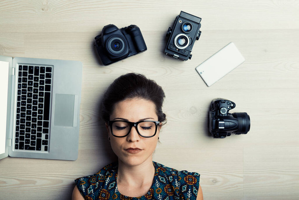 Окруженная устройствами, молодая женщина символизирует важность имиджевой культуры в современных социальных сетях, от vlogging до создания контента - Фото, изображение