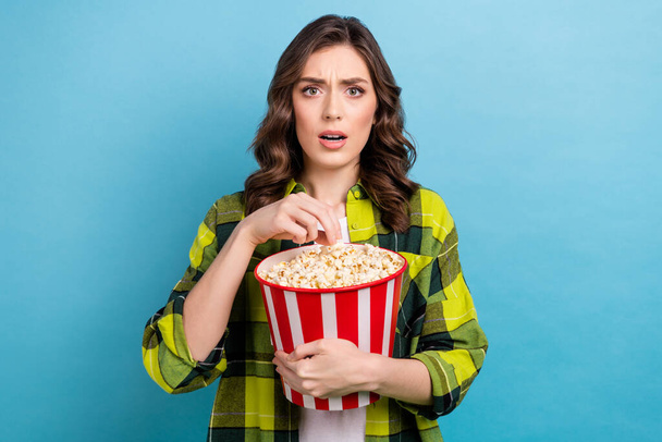 Photo of scared shocked lady wear checkered jacket eating pop corn watching scary movie isolated blue color background. - Fotografie, Obrázek
