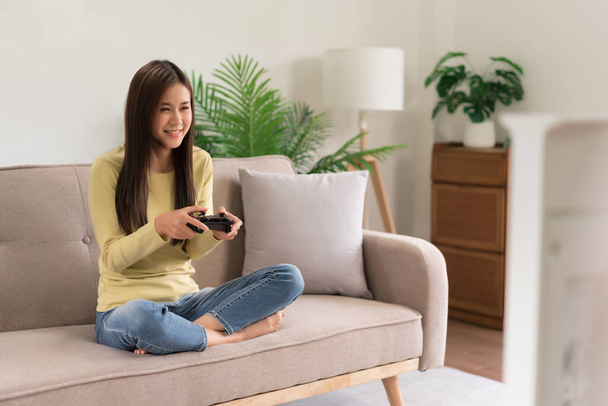 Leisure activity concept, Young woman sitting on couch to playing video games with joystick console. - Fotografie, Obrázek