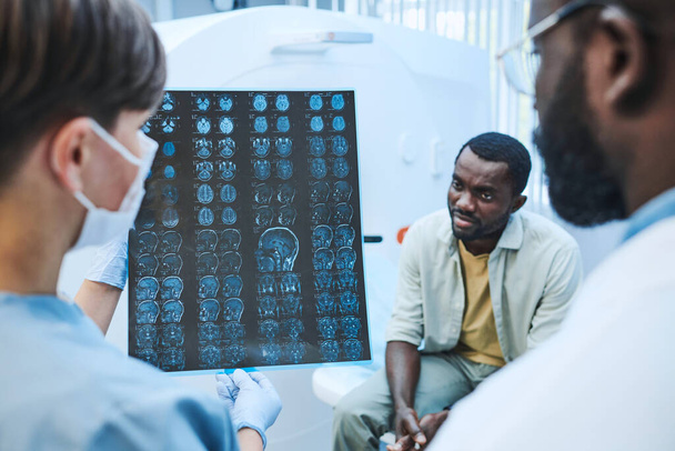 Equipo de neurólogos analizando tomografía computarizada cerebral del paciente afroamericano en el hospital - Foto, Imagen