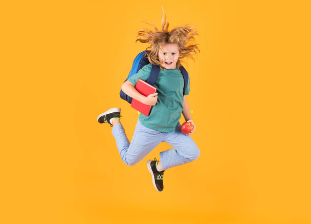 Повернутися до школи. Повноцінне тіло веселого школяра стрибає назад до школи ізольовано на жовтому тлі
 - Фото, зображення