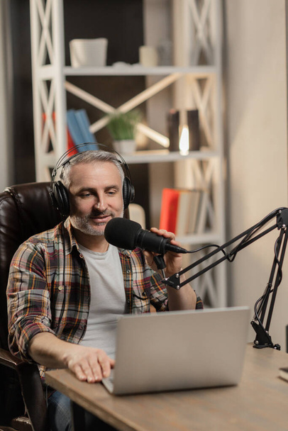 Senior man in casual outfit streaming from studio. Blogger in headphones is recording podcast. High quality photo - Photo, Image