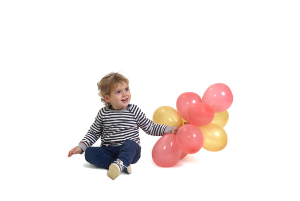 vista frontal del niño jugando con un globo aerostático en el suelo sobre fondo blanco - Foto, imagen