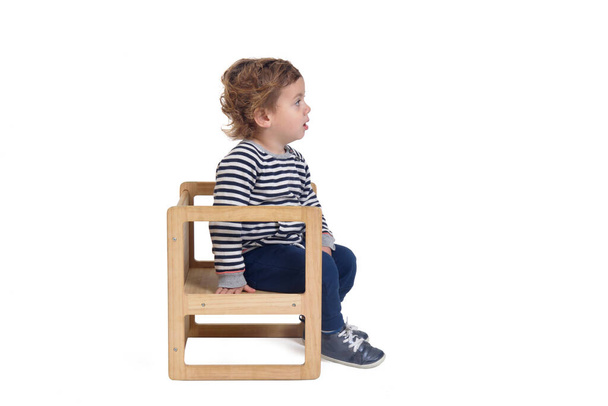 zijaanzicht van een baby jongen zittend op stoel op witte achtergrond - Foto, afbeelding