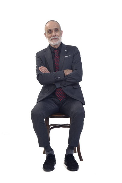 front view of a man sitting  on chair with suit and tie with arms crossed on white background - Foto, Imagem