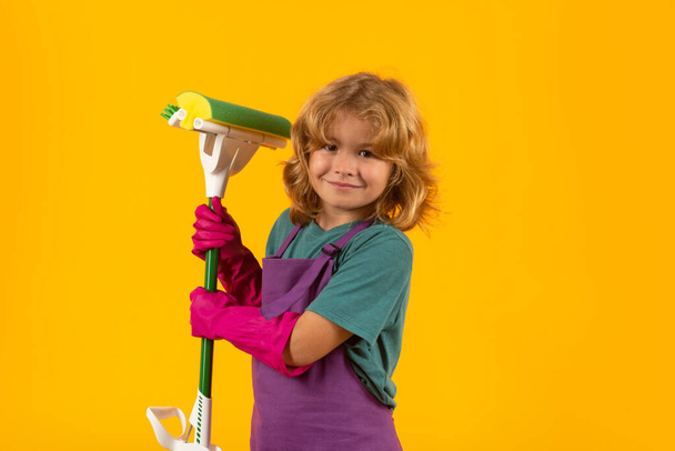 Çocuk temizliği, konsept büyüme, gelişim, aile ilişkileri portresi. Oda servisi ve ev temizliği konsepti. Çocuk temizlik için toz bezi ve eldiven kullanıyor. Stüdyo izole edilmiş arka plan - Fotoğraf, Görsel