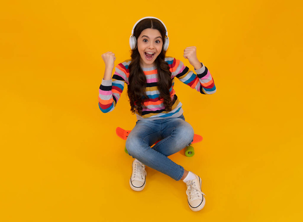 Funny kid girl 12, 13, 14 years old listen music with headphones. Teenage girl with headphones listening songs on headset earphone. Urban kids style, stylish hipster teen - 写真・画像