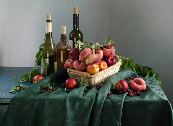still life with red and green apples and grapes in a basket on a wooden table - 写真・画像