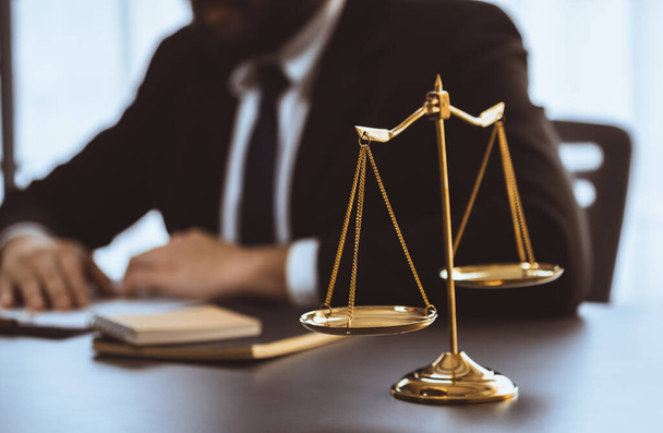 Focus shiny golden balanced scale on blurred background of lawyer working in his desk at law firm office. Scale balance for righteous and equality judgment by lawmaker and attorney. Equilibrium - Φωτογραφία, εικόνα