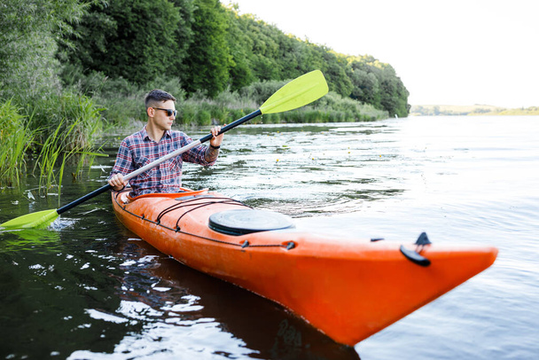 Kayak sul fiume. Un giovane caucasico siede in kayak e remi. Il concetto di intrattenimento acquatico. - Foto, immagini