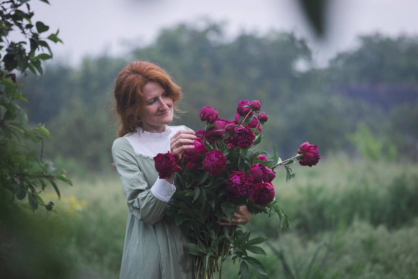 beautiful girl with a bouquet of peonies in the garde - Zdjęcie, obraz