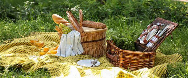 Wicker baskets with tasty food and drink for romantic picnic in park - Photo, Image