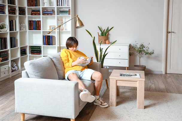 Adolescente ragazzo lettura libro sul divano a casa - Foto, immagini