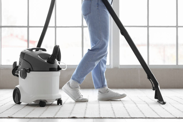 Young woman vacuuming carpet at home - Foto, Imagen