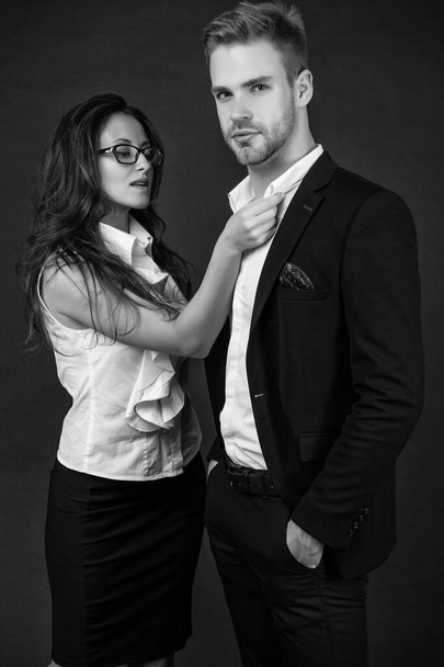 stylish man and woman in business look on black background, love. - Valokuva, kuva