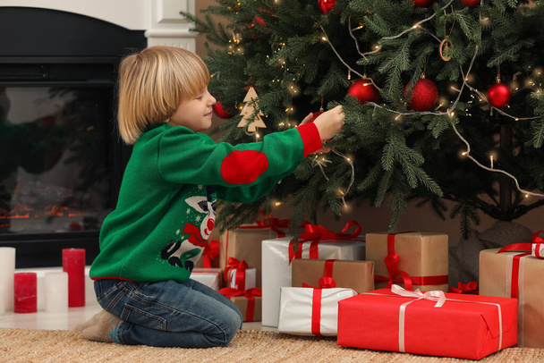 Little child decorating Christmas tree at home - 写真・画像