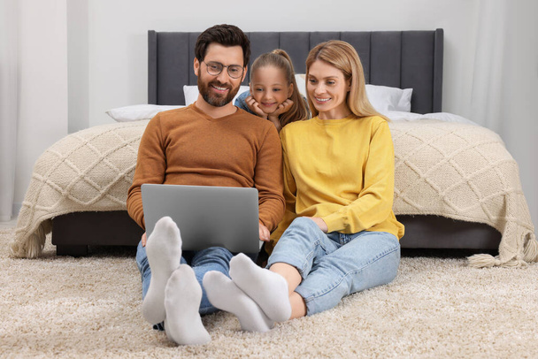 Happy family with laptop on floor at home - Foto, Bild