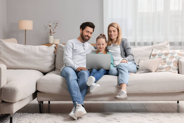 Happy family with laptop on sofa at home - Фото, изображение
