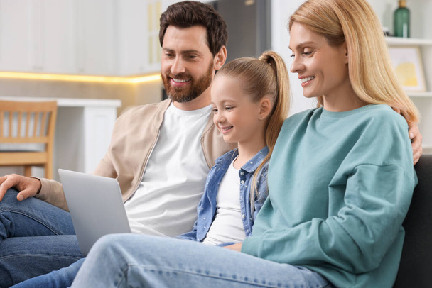 Happy family spending time together and using laptop on sofa at home - Fotoğraf, Görsel