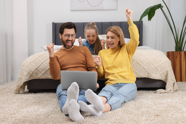 Emotional family with laptop on floor at home - Photo, image