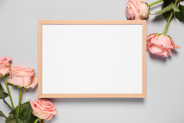 Empty photo frame and beautiful flowers on light background, flat lay. Space for design - Foto, immagini
