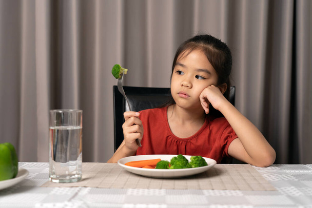 Little cute kid girl refusing to eat healthy vegetables. Children do not like to eat vegetables. - Foto, immagini