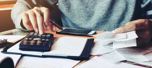 Hombre usando la calculadora y calcular facturas en la oficina en casa
. - Foto, Imagen