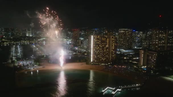 New Year Eve in Honolulu city. People celebrating with sparkling fireworks on Oahu island during Hawaiian vacation. Bright explosion of fireworks in urban skyline. Aerial view Fireworks Waikiki beach - Footage, Video