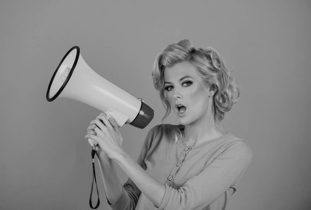 Blonde woman in retro style shouting through a megaphone. Beauty woman with megaphone isolated on pink - Zdjęcie, obraz
