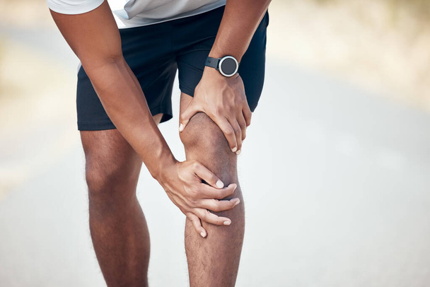 Running, knee pain and closeup of man in city for inflammation, accident and emergency. Fitness, workout and training with legs of male runner in road for muscle ache, sports injury and first aid. - Foto, immagini