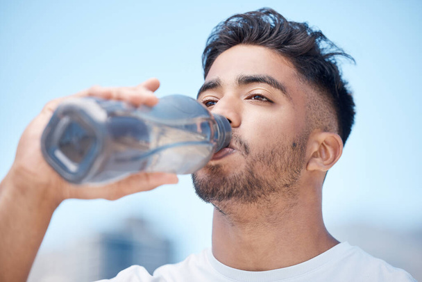 Man, fitness and drinking water in city for sustainability after running exercise, workout or training outdoors. Thirsty male person, athlete or runner with drink for hydration, rest or break in town. - Zdjęcie, obraz