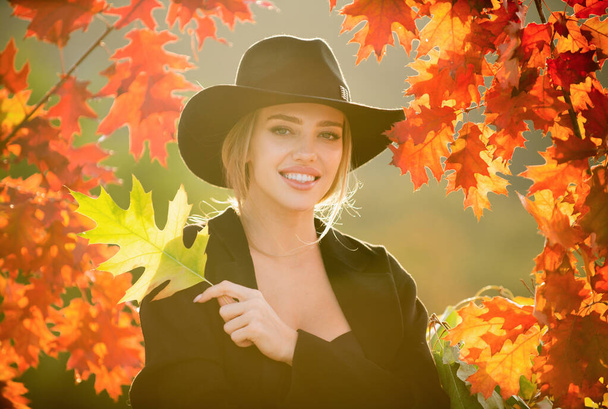 Happy smiling young woman in park on sunny autumn day. Carefree young girl in trendy vintage hat laughing. Girl in good autumn mood posing in autumn park outdoor, enjoying good weather - Fotó, kép
