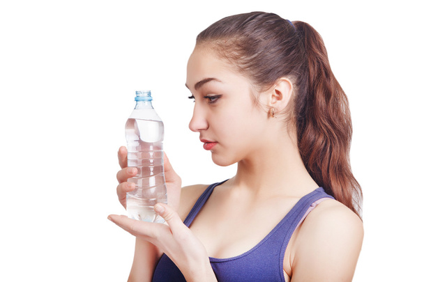 Beautiful athletic girl looks hold a bottle - Zdjęcie, obraz