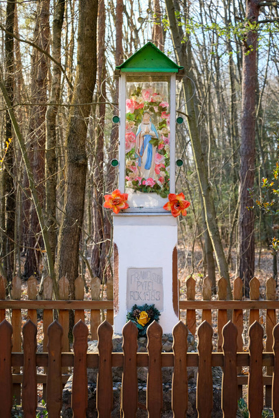Een kapel langs de weg in het bos, een Maria met een rozenkrans en bloemen, overal bloemen, Polska kapliczka - Foto, afbeelding