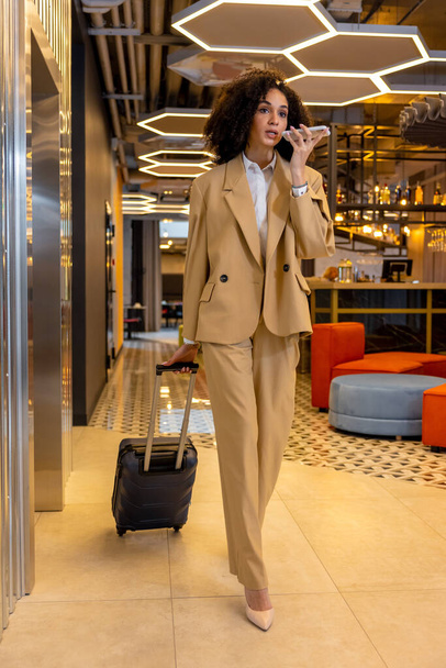 Arrival. Good-looking young business woman with a suitcase in the hotel - Φωτογραφία, εικόνα