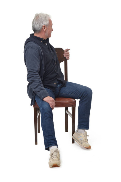 man sitting on a chair from the front who turns and looks into the background on white background - Foto, afbeelding