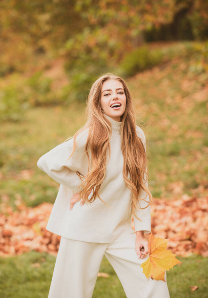 Autumn vogue. Young stylish hipster girl wearing modern dress in urban park smiling happy. Caucasian female model. Fall fashion - 写真・画像
