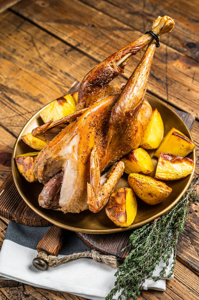 Roasted guinea fowl with herbs and potato, cooked farm eco bird. Wooden background. Top view. - Foto, imagen