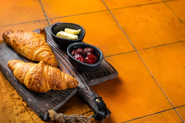 Delicious breakfast with fresh croissants served with butter and jam. Orange background. Top view. Copy space. - Photo, Image