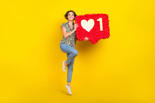 Full length photo of sweet shiny woman dressed zebra striped shirt jumping high holding feedback pinata isolated yellow color background. - Foto, Imagen