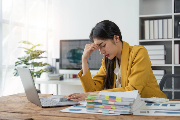 Οι γυναίκες των επιχειρήσεων είναι τόνισε, ενώ εργάζονται σε φορητό υπολογιστή και σωρός εγγράφων, Κουρασμένη επιχειρηματίας με πονοκέφαλο στο γραφείο, αίσθημα ασθένειας στην εργασία. - Φωτογραφία, εικόνα
